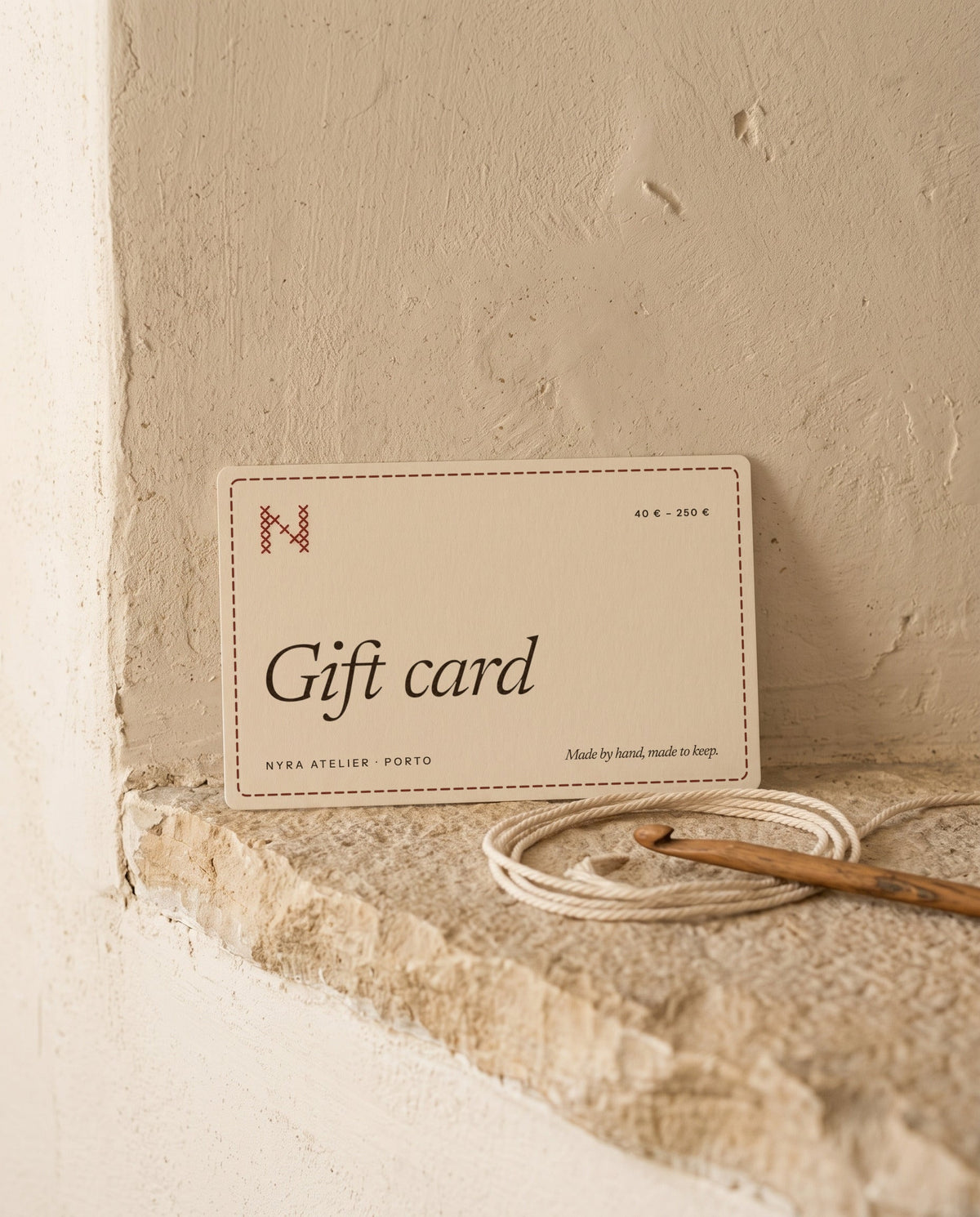 Nyra Atelier gift card, 40 € to 250 €, on a limestone ledge with cotton cord and a crochet hook (AI setting)