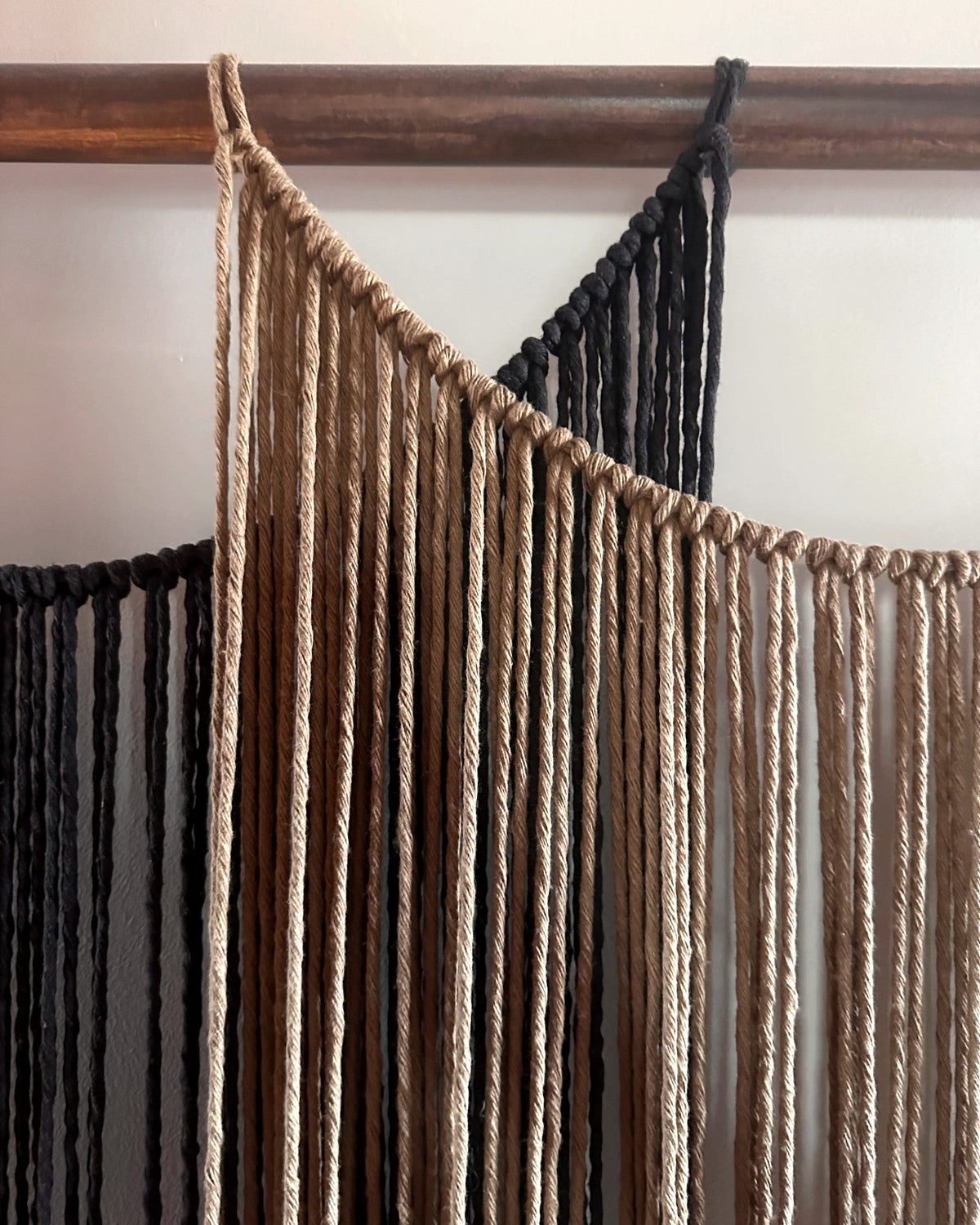 Close-up of the caramel macramé panel of Suspenso Terra by Nyra Atelier, knotted along a draped curve, with the charcoal panel behind