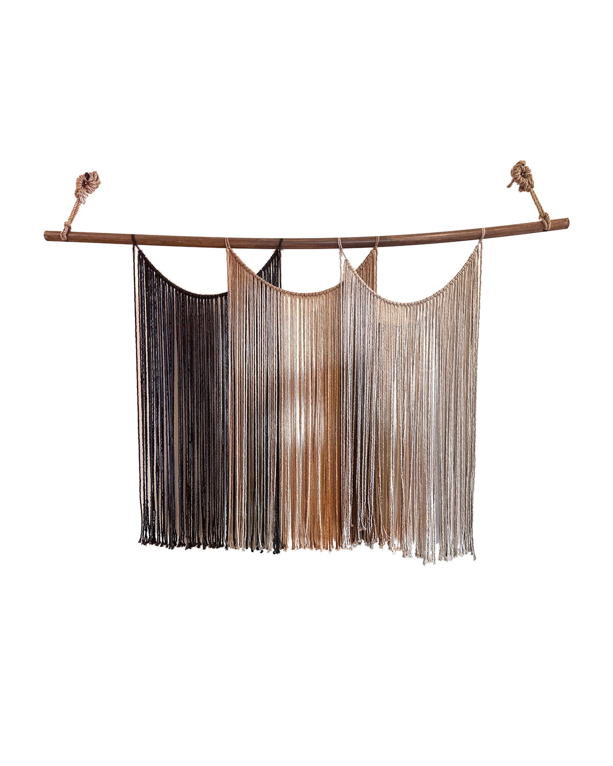 Suspenso Terra, a large handmade macramé wall hanging in deep brown, caramel and taupe cord on a natural wooden branch, photographed on a plain white wall