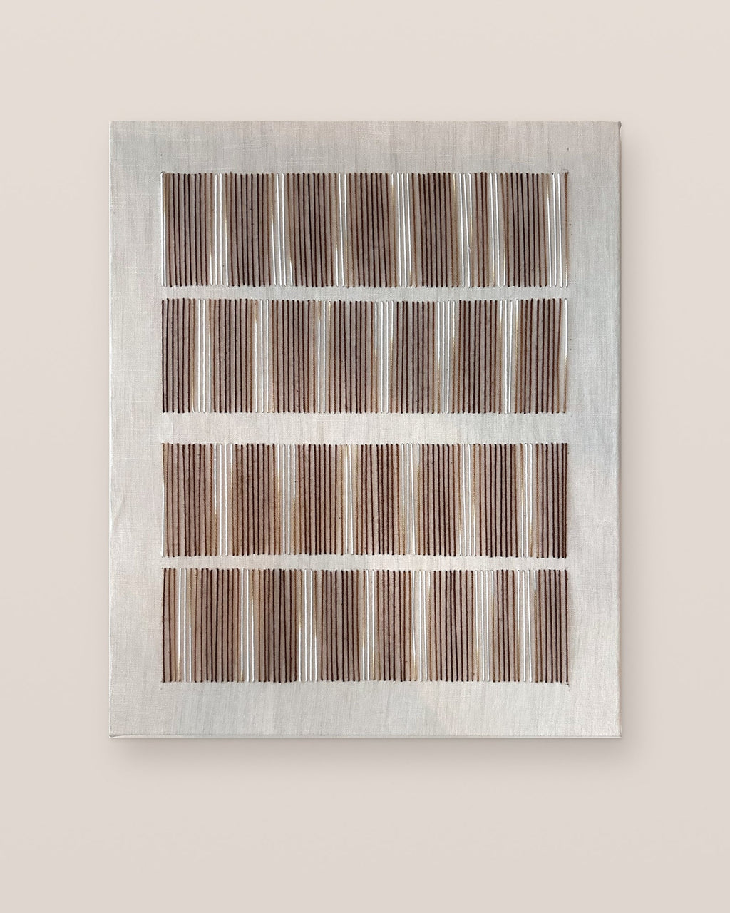 Andante von Nyra Atelier, handgemachte Textil-Wandkunst, vertikal aufgehängt: vier Reihen kurzer, handgestickter Linien aus brauner, karamellfarbener und cremefarbener Wolle auf einer naturfarbenen Leinwand aus Baumwolle und Wolle