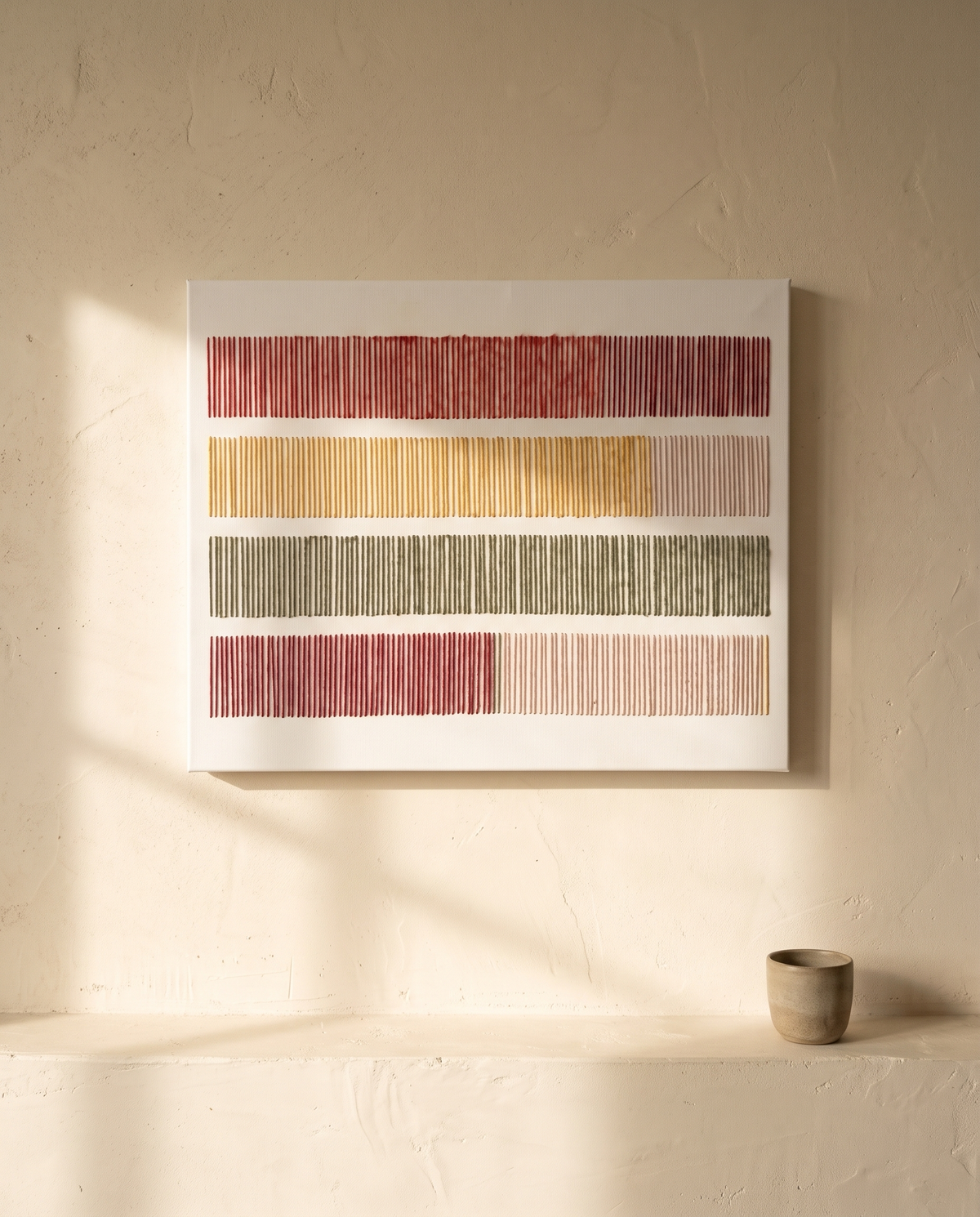 Cadence, hand-embroidered textile wall art by Nyra Atelier, on a cream lime-plaster wall above a limestone ledge in late-afternoon light