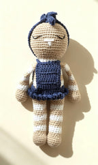 Mia, handmade crochet bunny in her navy blue dress and bow headband, standing against a warm cream background