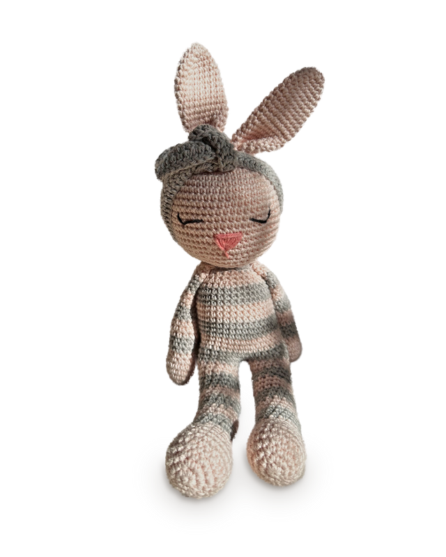Luna, a handmade crochet bunny by Nyra Atelier in soft grey-and-blush stripes with pale pink ears, a pink stitched nose and a grey knotted headband, seated