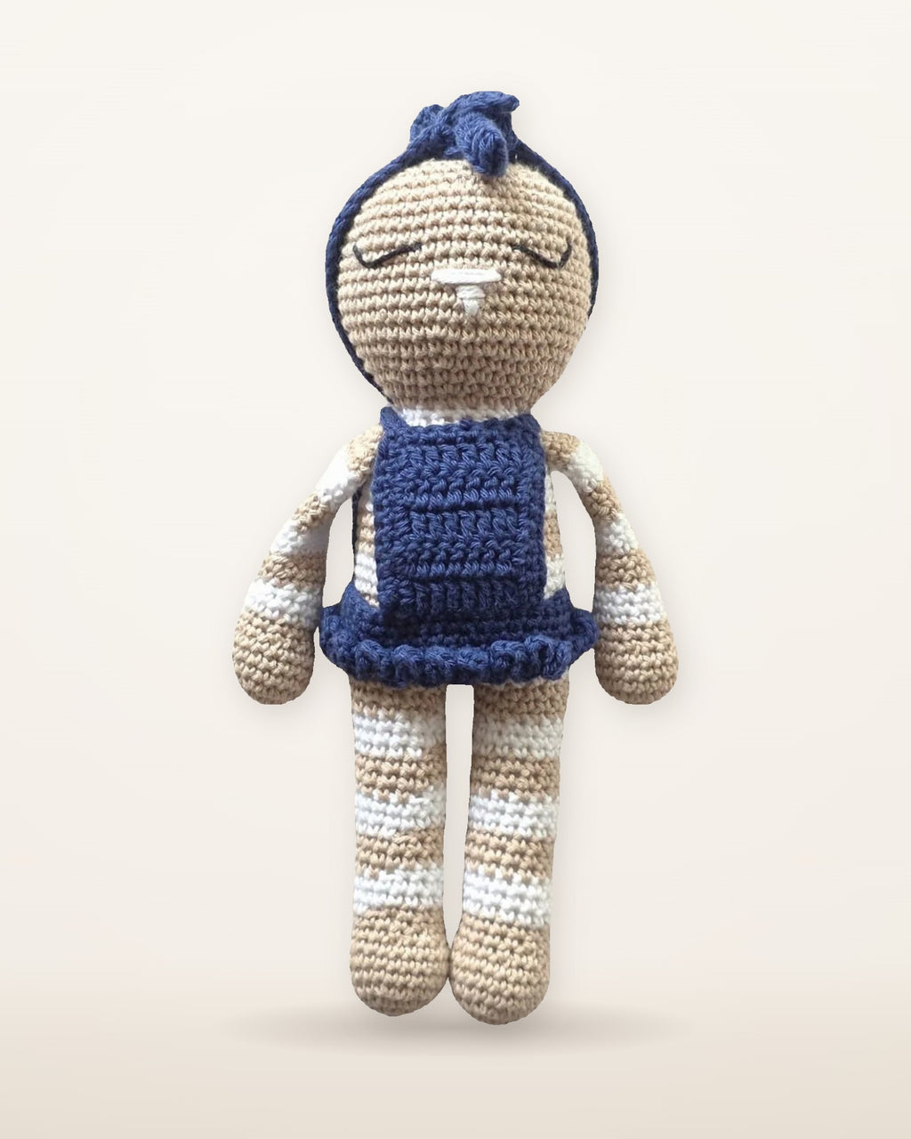 Mia, handmade crochet bunny by Nyra Atelier, in her removable navy blue ruffled dress and bow headband, studio photo on a warm ivory background