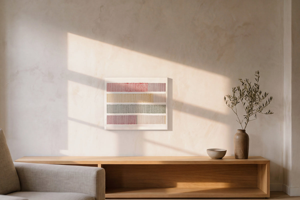 Cadence, hand-embroidered wool on stretched canvas, on a lime-plaster wall above a low oak console, crossed by late-afternoon window light. AI setting: the room was created with AI; the piece is a real photograph.