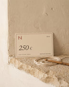 Nyra Atelier gift card for 250 €, on a limestone ledge with cotton cord and a crochet hook (AI setting)