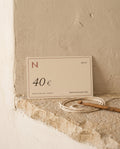Nyra Atelier gift card for 40 €, on a limestone ledge with cotton cord and a crochet hook (AI setting)