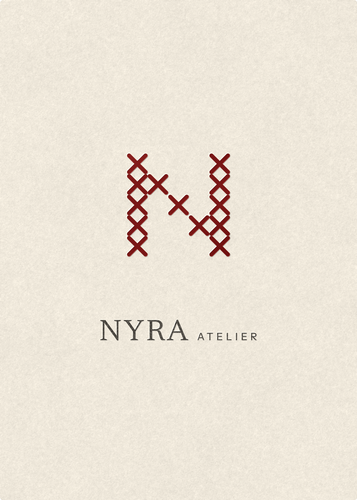 O cartão-oferta Nyra Atelier: papel de algodão marfim com um N vermelho em ponto de cruz e as palavras Nyra Atelier