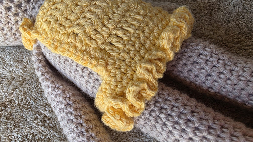 Close-up of the ruffled hem of Sol's removable yellow crochet dress