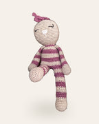 Rosa, handmade crochet bunny by Nyra Atelier with pink and beige stripes and a pink bow, sitting with one leg tucked in. Real photo, cut out on a warm ivory background.