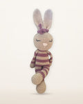 Rosa, handmade crochet bunny by Nyra Atelier with pink and beige stripes, tan ears and a pink bow, studio photo on a warm ivory background