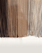The long fringe of Suspenso Terra in its three tones, deep brown, caramel and soft taupe-grey. Real photograph.