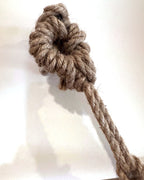 The knotted natural rope that hangs Suspenso Terra, coiled at the top where it sits on a wall hook. Real photograph.